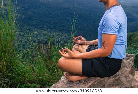 Man training yoga and meditation on the rock at the mountain ( selective focus )