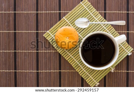 Black coffee in white mug with spoon and cupcake bakery on wooden