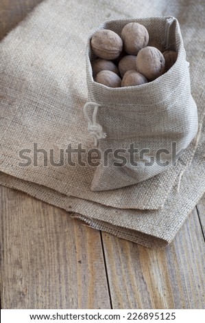 Walnuts in a cotton bag on sackcloth, which lies on a wooden table.