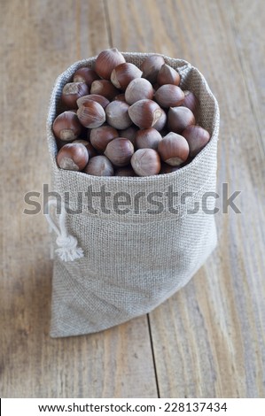 Hazelnuts in a cotton bag on a wooden table, close-up.