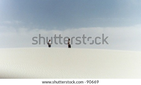 Two men atop a large dune at White Sands, New Mexico.