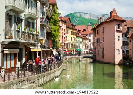 ANNECY, FRANCE - MAY 13: People walk on the Quai de l'Isle and look to swan family in the center of the Old town on May 13, 2012 in Annecy, France. Annecy is one of the most beautiful towns in France.