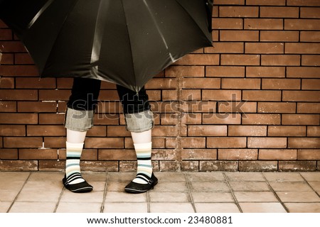 Woman with striped socks hiding behind umbrella. Artistic vintage post processing.