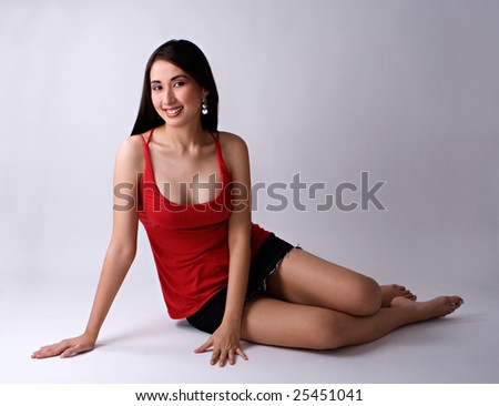 Sexy Asian woman, seated on floor, wearing red top and mini skirt