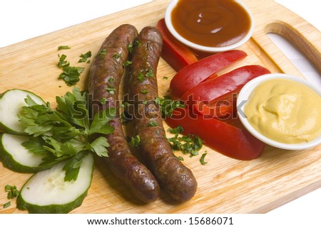 Two long frankfurters with pepper, cucumber, herbs and two kinds of sauces - mustard and ketchup on wooden board