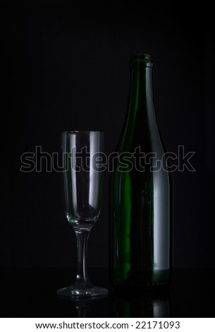 Champagne bottle with glass on black ground