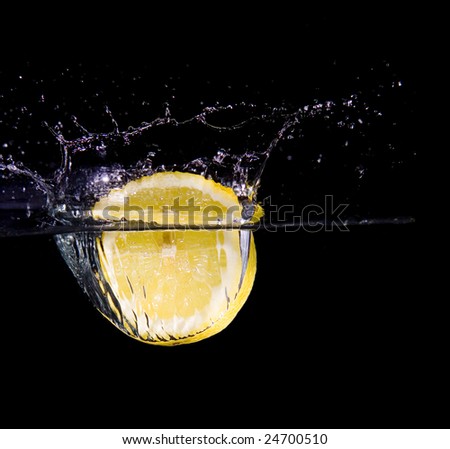 Lemon slice in water with bubbles on black ground