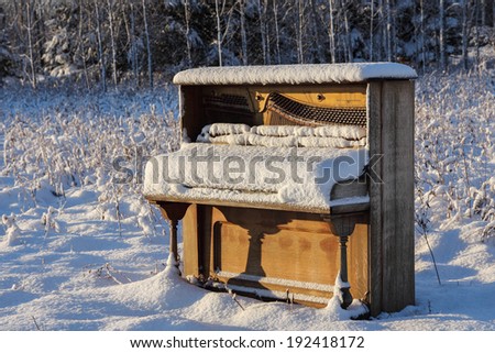 Abandoned Piano in Winter Field - upright piano that has been abandoned in a snowy winter field / meadow.