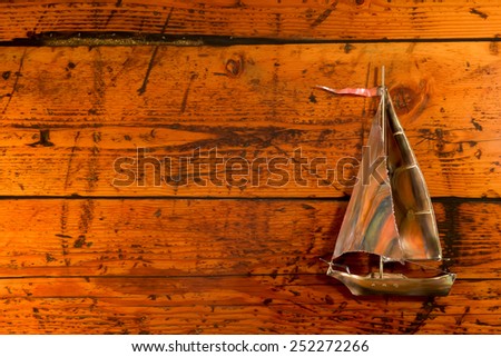 Sailboat on Textured Wood - Copper sailboat set against a highly textured wood background.  Vibrant color, texture, and lighting with copy space on left.