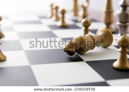 Classic chess game - fallen gold king on chessboard