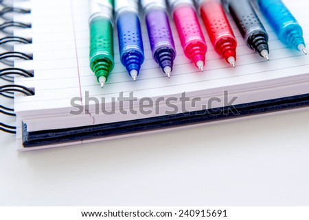 back to school supplies, bright multi colored pens and a spiral notebook