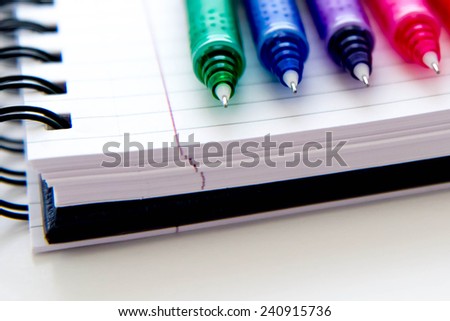 back to school supplies, bright multi colored pens and a spiral notebook