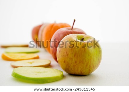 line of red and green apples and slices with one orange