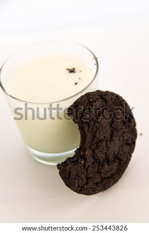 chocolate cookie missing a bite and milk
