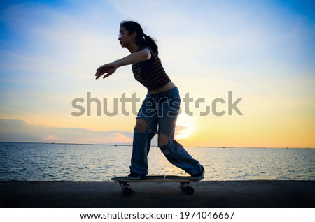 Happy and funny Young woman play surf board or surf skate board on bridge along seashore aginst sunset