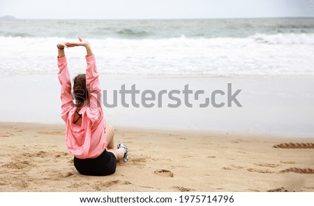 Back view of happy woman site relax and exercise on beach , lift hand up and stretching