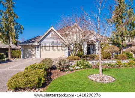 Beautiful exterior of newly built luxury home. Yard with green grass and walkway lead to front entrance.