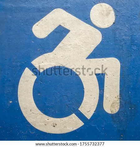 Square Close up of blue and white handicapped sign painted on a gray surface