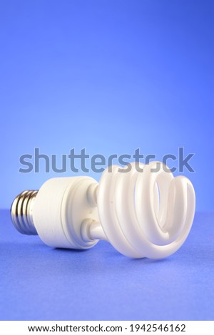 A CFL Compact Fluorescent Lightbulb over a soft blue background.