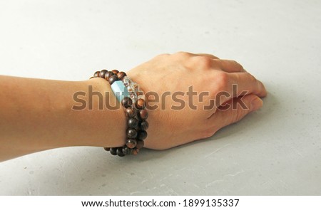Bracelet made of wooden beads on a woman\'s hand, bracelet made of natural stones, natural aquamarine and rhinestone. Bracelet made of stones. Handmade jewelry bracelets on light background.