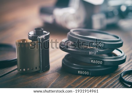 Old photo film cassette, photo filters, vintage camera on background, selective focus.