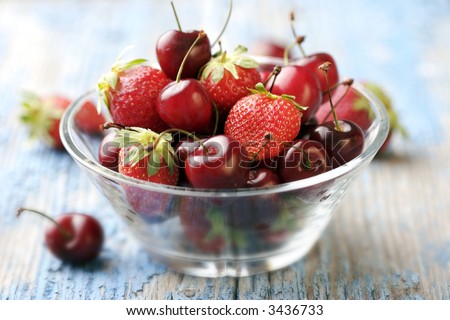 modern glass-bowl on a rustic table filled with seasonal red fruit