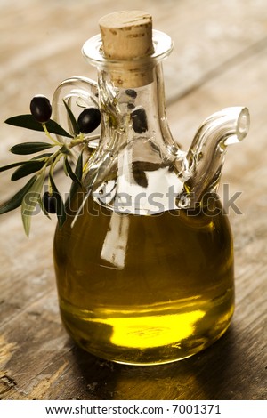 bottle of olive oil on old wooden table and an olive branch