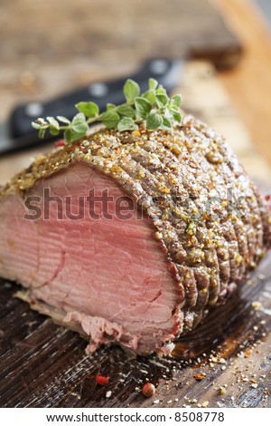juicy rare roast beef covered in herbs and pepper