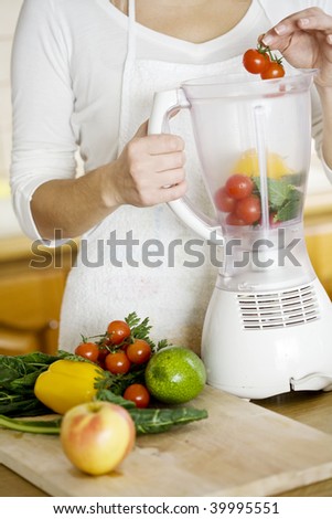 female putting vegetables in blender