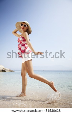 young female in retro outfit, jumping around on the beach