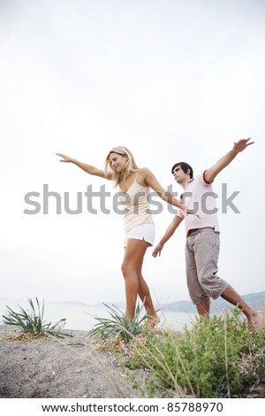 couple walking along the beach keeping balance with their hands