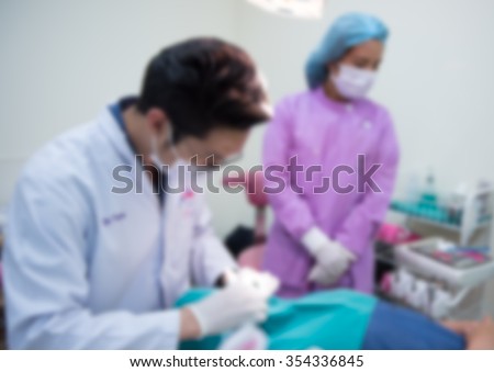 Blurred abstract background of dentistry care unit room interior in dental hospital/ clinic with dentist and assistants working on patient\'s tooth care using equipment, instrument on dental chair