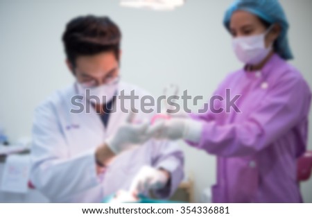 Blurred abstract background of dentistry care unit room interior in dental hospital/ clinic with dentist and assistants working on patient\'s tooth care using equipment, instrument on dental chair