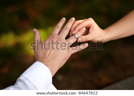 closeup of hands putting ring on finger