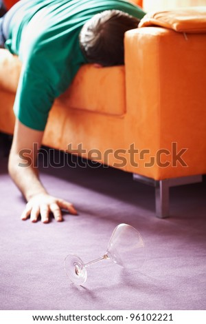 guy sleeping on the sofa with a glass on the floor