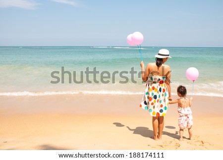 Mother and  kid on the beach with pink balloons, happy mothers day