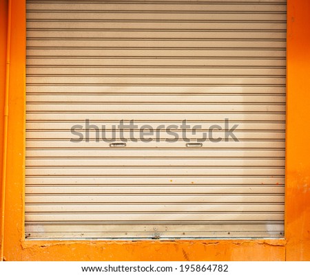 a shuttered roll up metal door with orange wall