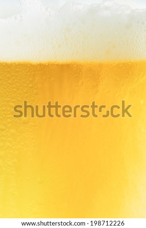Glass of fresh beer with cap of foam on white background