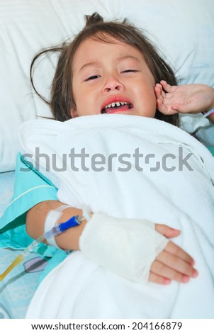 Sick little girl cry on hospital bed and hand with intravenous injection