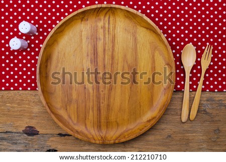 Wooden plate, tablecloth, spoon, fork on old table background