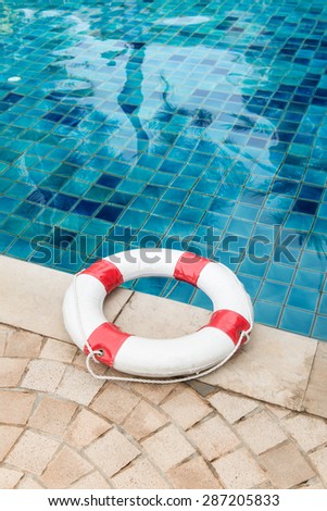 Life preserver white red lifebuoy with white ropes on tiled floor near swimming pool