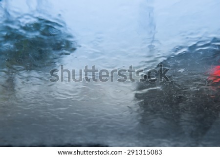 Blurry car silhouette seen through water drops on the car windshield