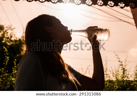 Thirsty woman drinking water from bottle  on summer hot day