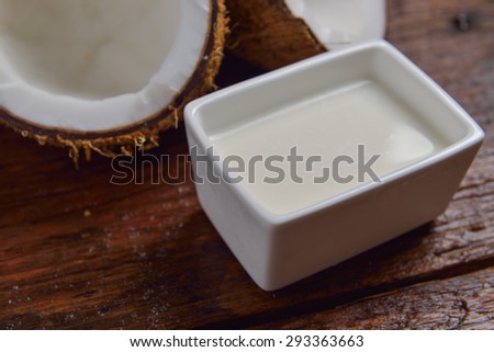 Coconut and coconut milk in square white bowl on wooden table