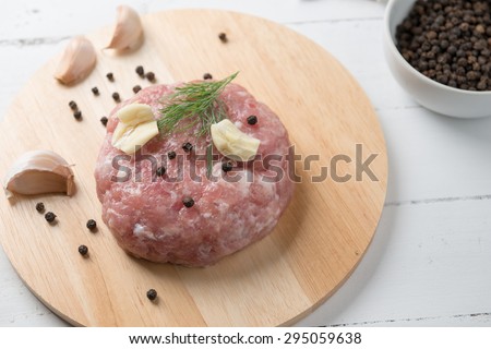 Ground pork hamburger on chopping block with pepper