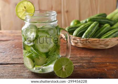 Detox water with lime and cucumbers in a mason jar against a rustic wood background