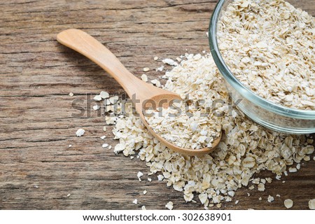 Cup of dry rolled oat flakes oatmeal on old wooden table