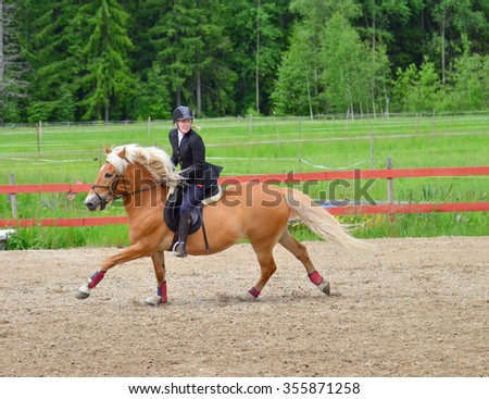 Woman horseback riding on riding arena