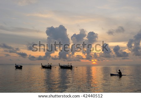Thailand. Phi Phi island. Magic sunrise landscape with thai boats and a silhouette of alone kayaker