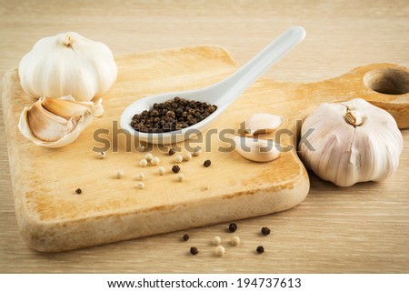 Black peppercorns on spoon and garlic